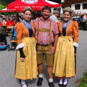 Festwirt und Obmann der BMK-Brandenberg Thomas Brill schmückt sich mit den beiden feschen Marketenderinnen der BMK Kramsach